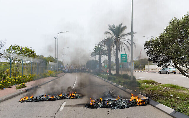 Des Israéliens bloquent l'entrée du port d'Ashdod en brûlant des pneus sur la chaussée lors d'une manifestation contre la refonte judiciaire, le 23 mars 2023. (Crédit : Flash90) Des Israéliens bloquent l'entrée du port d'Ashdod en brûlant des pneus sur la chaussée lors d'une manifestation contre la refonte judiciaire, le 23 mars 2023. (Crédit : Flash90)