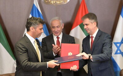 Le Premier ministre Benjamin Netanyahu applaudissant alors que le ministre des Affaires étrangères Eli Cohen et l'ambassadeur des Émirats arabes unis en Israël Mohamed al-Khaja échangent des copies signées de l'accord douanier entre les deux pays, le 26 mars 2023. (Crédit : Amos Ben Gershom/GPO)