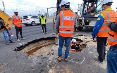 Des travailleurs sur l’autoroute Ayalon de Tel Aviv dépêchés pour examinent et combler le trou qui s'est formé sur la route, le 19 mars 2023. (Crédit : Ayalon Highways Co.)
