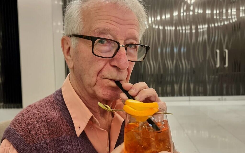 Gidon Lev boit un Aperol spritz dans le hall d'un hôtel pendant une interview avec le Times of Israel, le 24 janvier 2023. (Crédit : Autorisation de Julie Gray)