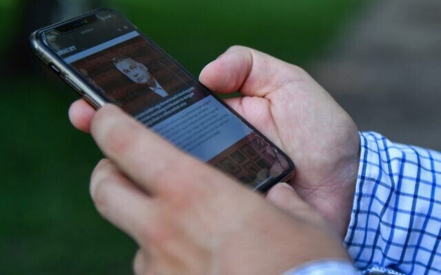Le journaliste d'investigation hongrois  Szabolcs Panyi, dont le numéro de téléphone figurait sur une liste de personnalités prise pour cible par un logiciel espion israélien, regarde son téléphone mobile à Budapest, le 20 juillet 2021. (Crédit : GERGELY BESENYEI / AFP)