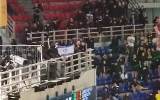 Des supporters de l'AEK Athènes brûlent un drapeau israélien lors d'un match contre Hapoel Jérusalem, à Athènes, en Grèce, le 12 avril 2023. (Crédit : Capture d'écran de la vidéo Twitter : utilisée conformément à l'article 27a de la loi sur le droit d'auteur) Des supporters de l'AEK Athènes brûlent un drapeau israélien lors d'un match contre Hapoel Jérusalem, à Athènes, en Grèce, le 12 avril 2023. (Crédit : Capture d'écran de la vidéo Twitter : utilisée conformément à l'article 27a de la loi sur le droit d'auteur)