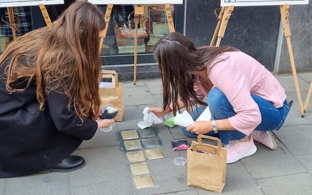 Des bénévoles juifs nettoyant des Stolpersteine (pierres d'achoppement) à Bruxelles, en Belgique, lors d'un événement de nettoyage des Stolpersteine organisé conjointement avec l'Association juive européenne à l'occasion de Yom HaShoah, le 27 avril 2022. (Crédit : Make Their Memory Shine)