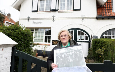 La guide touristique belge Brigitte Hochs montre une photo du scientifique Albert Einstein le 20 avril 2023 à De Haan/Le Coq, devant la villa "Savoyarde" où le célèbre scientifique allemand a vécu pendant six mois en 1933 après avoir quitté l'Allemagne. (Crédit : Kenzo TRIBOUILLARD / AFP)