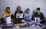 Bahar Elias, une femme irakienne déplacée de 40 ans appartenant à la communauté yazidi, posant pour une photo avec son fils et ses filles tout en tenant des photos d'autres membres de sa famille enlevés par le groupe terroriste sunnite État islamique (EI), lors d'un entretien au camp de Sharya, à une quinzaine de kilomètres près de la ville de Dohuk, dans le nord de l'Irak, sur une  photo prise le 22 avril 2023. (Crédit : Safin Hamed/AFP)