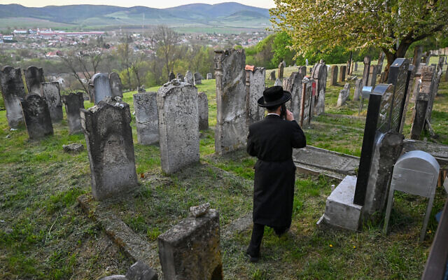 Un pèlerin juif hassidique marche dans le cimetière juif près de la tombe de feu le rabbin miracle Yeshaya Steiner, également connu sous le nom de Rebbe Shayale, dans le village de Bodrogkeresztur, en Hongrie, le 23 avril 2023, lors d'un pèlerinage de juifs hassidiques à l'occasion du 98e anniversaire de la mort du rabbin Steiner. (Crédit : ATTILA KISBENEDEK / AFP) Un pèlerin juif hassidique marche dans le cimetière juif près de la tombe de feu le rabbin miracle Yeshaya Steiner, également connu sous le nom de Rebbe Shayale, dans le village de Bodrogkeresztur, en Hongrie, le 23 avril 2023, lors d'un pèlerinage de juifs hassidiques à l'occasion du 98e anniversaire de la mort du rabbin Steiner. (Crédit : ATTILA KISBENEDEK / AFP)
