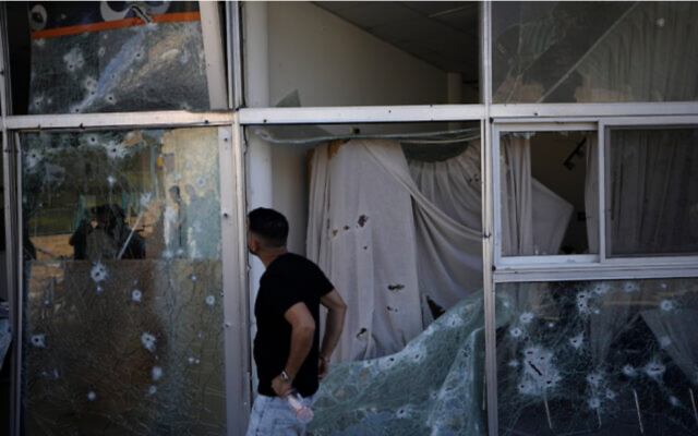 Un homme inspectant les dommages causés à un centre commercial par une roquette tirée depuis le Liban à Shlomi, dans le nord d'Israël, le 6 avril 2023. (Crédit : AP Photo/Ariel Schalit)