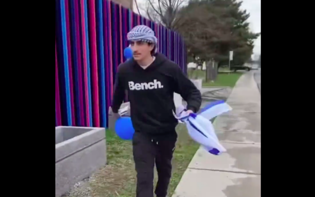 L’individu qui a volé et brûlé des drapeaux israéliens à Montréal, le 26 avril 2023. (Crédit : Twitter)