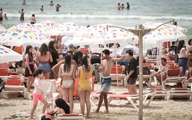 Des Israéliens se pressant sur la plage de Tel Aviv par une chaude journée, pendant les vacances de Pesssah, le 9 avril 2023. (Crédit : Avshalom Sassoni/FLASH90)