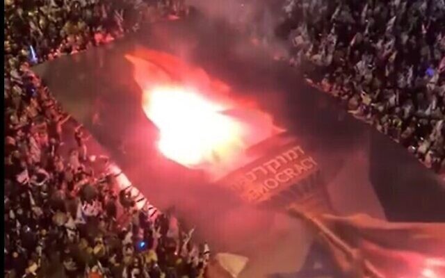 Des Israéliens manifestent contre le projet du gouvernement du Premier ministre Benjamin Netanyahu de réformer en profondeur le système judiciaire et déroulent une bannière sur laquelle on peut lire "Flambeau de la démocratie", pendant Yom HaAtsmaout, le 25 avril 2023. (Capture d'écran Twitter. utilisée conformément à l'article 27a de la loi sur le droit d'auteur)