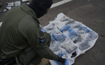 Un membre de l'unité Magen inspecte des armes saisies par les forces de sécurité israéliennes pendant une tentative de trafic d'armes le long de la frontière avec la Jordanie, le 20 avril 2023. (Crédit : Israel Police)