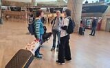 Des militants israéliens accueillant les passagers, pour discuter du remaniement judiciaire en cours dans le pays, à leur arrivée à l'aéroport international Ben Gurion, le 21 avril 2023. (Crédit : Ben Gurion Airport Ask Me About Democracy Team)