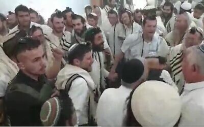 Le ministre des Finances Bezalel Smotrich (au centre) et le député Zvi Souccot (à sa gauche) dansent lors d'un office de prière marquant le jour de l’Indépendance à Homesh, dans le nord de la Cisjordanie, le 26 avril 2023. (Crédit : Capture d'écran utilisée conformément à la clause 27a de la loi sur le droit d'auteur)