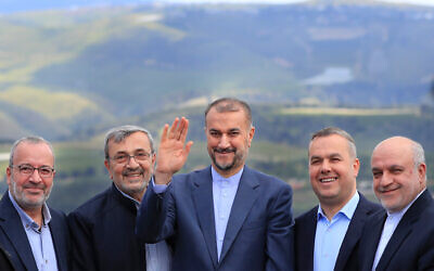 Le ministre iranien des Affaires étrangères, Hossein Amir Abdollahian, au centre, saluant des membres du Hezbollah et des législateurs libanais, avec le côté israélien de la frontière en arrière-plan, lors de sa visite au village de Maroun el-Rass, à la frontière israélo-libanaise, au Sud-Liban, le 28 avril 2023. (Crédit : AP Photo/Mohammed Zaatari)