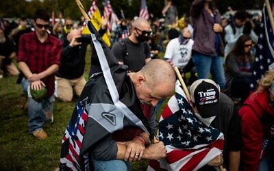 Des gens s'agenouillant pendant qu'un organisateur lit une prière à la foule de plusieurs centaines de personnes rassemblées lors d'un rassemblement des Proud Boys, à Delta Park à Portland, dans l'Oregon, le 26 septembre 2020. (Crédit : Maranie R. STAAB/AFP)