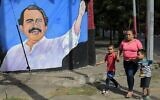 Une femme et des enfants passent devant une fresque murale représentant le président du Nicaragua, Daniel Ortega, à Managua, le 10 janvier 2022, premier jour de son quatrième mandat. (Crédit : Oswaldo RIVAS / AFP)