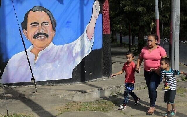 Une femme et des enfants passent devant une fresque murale représentant le président du Nicaragua, Daniel Ortega, à Managua, le 10 janvier 2022, premier jour de son quatrième mandat. (Crédit : Oswaldo RIVAS / AFP) Une femme et des enfants passent devant une fresque murale représentant le président du Nicaragua, Daniel Ortega, à Managua, le 10 janvier 2022, premier jour de son quatrième mandat. (Crédit : Oswaldo RIVAS / AFP)