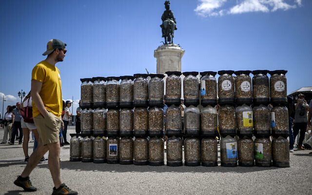 Des conteneurs remplis de mégots de cigarettes collectés en une semaine sont exposés sur la place Comercio à Lisbonne le 23 avril 2023. Des militants écologistes ont rassemblé en une semaine environ 650 000 mégots de cigarettes et les ont entassés aujourd'hui sur une place du centre de Lisbonne pour sensibiliser contre ce type de pollution. (Crédit : PATRICIA DE MELO MOREIRA / AFP)