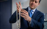 Rahul Kadakia, responsable international de la joaillerie chez Christie's, tenant un collier en perles naturelles et de culture et avec un diamant coloré de Harry Winston, qui devrait rapporter au moins 7,2 millions de dollars lors de la vente World of Heidi Horten à Genève, le 8 mai 2023. (Crédit : Fabrice COFFRINI / AFP)