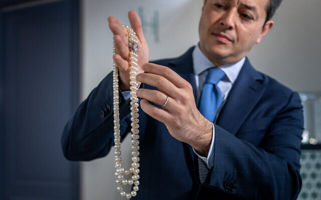 Rahul Kadakia, responsable international de la joaillerie chez Christie's, tenant un collier en perles naturelles et de culture et avec un diamant coloré de Harry Winston, qui devrait rapporter au moins 7,2 millions de dollars lors de la vente World of Heidi Horten à Genève, le 8 mai 2023. (Crédit : Fabrice COFFRINI / AFP)