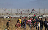 Des drapeaux palestiniens accrochés à la barrière de sécurité d’Israël lors d’une manifestation le long de la frontière avec Israël, à l’Est de Gaza, le 18 mai 2023, en réaction à la marche annuelle du drapeau israélien, en l'honneur du Jour de Jérusalem (Crédit : Mohammed ABED / AFP)