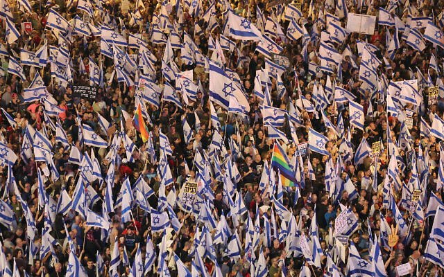 Des manifestants brandissant des drapeaux lors d'un rassemblement de protestation contre les projets de réforme du système judiciaire du gouvernement, à Tel Aviv, le 27 mai 2023. (Crédit : Jack Guez/AFP)