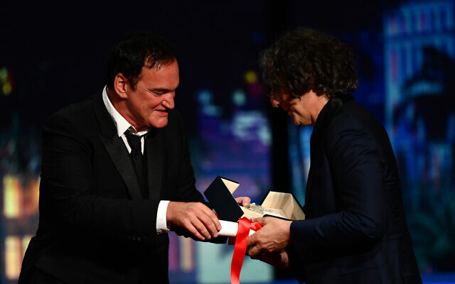 Le réalisateur britannique Jonathan Glazer, à droite, recevant le Grand Prix des mains du réalisateur américain Quentin Tarantino après avoir gagné pour le film "The Zone Of Interest" lors de la cérémonie de clôture de la 76e édition du Festival de Cannes à Cannes, dans le sud de la France, le 27 mai 2023. (Crédit : Christophe Simon/AFP)