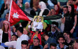 Un homme brandit une affiche de pré-mariage montrant le prince héritier de Jordanie Hussein et sa fiancée Rajwa al-Saif, lors d'un concert gratuit pour célébrer le prochain mariage au stade international d'Amman, le 29 mai 2023.  (Crédit : Khalil MAZRAAWI / AFP)