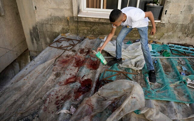 Un garçon regardant des taches de sang après un raid de l'armée israélienne dans le camp de réfugiés de Nur Shams près de la ville de Tulkarem, en Cisjordanie, le 6 mai 2023. (Crédit : AP Photo/Majdi Mohammed)