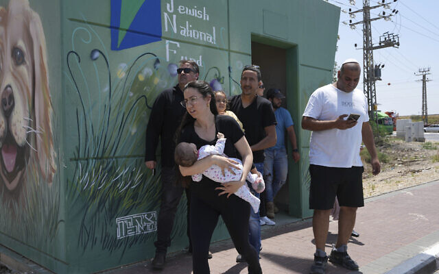 Des personnes quittant un abri entre les sirènes de raids aériens avertissant de l'arrivée de roquettes tirées depuis la Bande de Gaza, à Sderot, dans le sud d'Israël, près de la frontière avec Gaza, le 10 mai 2023. (Crédit : AP Photo/Tsafrir Abayov) Des personnes quittant un abri entre les sirènes de raids aériens avertissant de l'arrivée de roquettes tirées depuis la Bande de Gaza, à Sderot, dans le sud d'Israël, près de la frontière avec Gaza, le 10 mai 2023. (Crédit : AP Photo/Tsafrir Abayov)