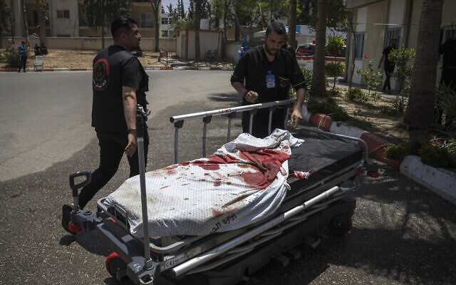 Des secouristes palestiniens tirant une civière ensanglantée après des frappes aériennes israéliennes, à Khan Younis dans la Bande de Gaza, le 10 mai 2023. (Crédit : AP Photo/Fatima Shbair) Des secouristes palestiniens tirant une civière ensanglantée après des frappes aériennes israéliennes, à Khan Younis dans la Bande de Gaza, le 10 mai 2023. (Crédit : AP Photo/Fatima Shbair)