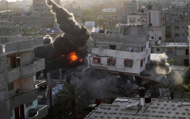 De la fumée et du feu s'échappant d'un immeuble qui appartenait à un responsable du Jihad islamique palestinien suite à une explosion causée par une frappe aérienne israélienne visant le bâtiment, à Gaza, le 13 mai 2023. (Crédit : AP Photo/Ashraf Amra) De la fumée et du feu s'échappant d'un immeuble qui appartenait à un responsable du Jihad islamique palestinien suite à une explosion causée par une frappe aérienne israélienne visant le bâtiment, à Gaza, le 13 mai 2023. (Crédit : AP Photo/Ashraf Amra)