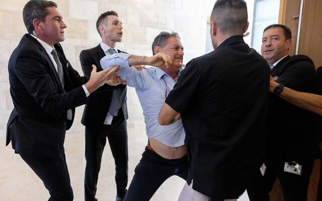 Hizky Sivak du Conseil régional d'Emek Hefer est sorti de force par des gardiens de la Knesset d'une réunion de la Commission des Finances consacrée au Fonds Arnona, le 15 mai 2023. (Crédit : Yonatan Sindel/Flash90) Hizky Sivak du Conseil régional d'Emek Hefer est sorti de force par des gardiens de la Knesset d'une réunion de la Commission des Finances consacrée au Fonds Arnona, le 15 mai 2023. (Crédit : Yonatan Sindel/Flash90)