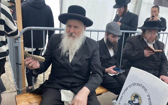 Un homme recueille des dons près de la tombe de Yeshaya Steiner à Bodrogkeresztur, en Hongrie, le 24 avril 2023. (Crédit : Yaakov Schwartz/ Times of Israel)