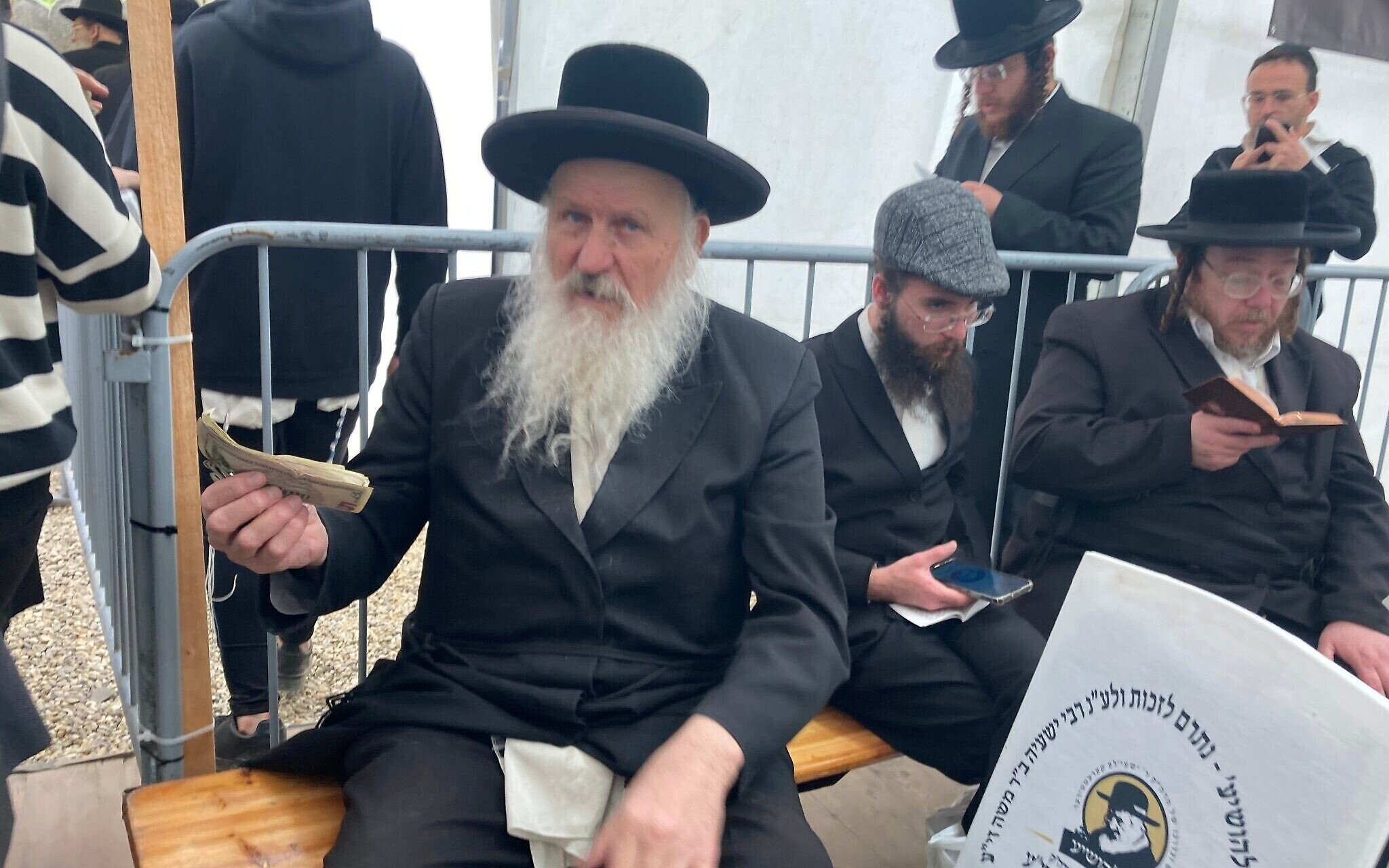 Un homme recueille des dons près de la tombe de Yeshaya Steiner à Bodrogkeresztur, en Hongrie, le 24 avril 2023. (Crédit : Yaakov Schwartz/ Times of Israel)