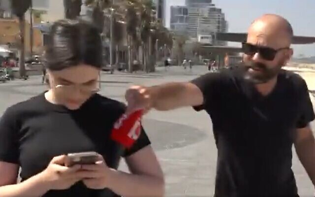 Un homme, à droite, arrachant la housse du microphone de la journaliste de la Treizième chaîne, Talya Cohen, avant d'asperger l'équipe de journalistes de gaz poivre, à Tel Aviv, le 10 mai 2023. (Crédit : Capture d'écran Twitter ; utilisée conformément à l'article 27a de la loi sur le droit d'auteur) Un homme, à droite, arrachant la housse du microphone de la journaliste de la Treizième chaîne, Talya Cohen, avant d'asperger l'équipe de journalistes de gaz poivre, à Tel Aviv, le 10 mai 2023. (Crédit : Capture d'écran Twitter ; utilisée conformément à l'article 27a de la loi sur le droit d'auteur)