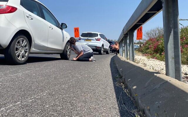 Des personnes s'accroupissant sur le bord de la route alors que les sirènes d'alerte à la roquette retentissent près de Tel Aviv, le 10 mai 2023. (Crédit : Shoshana Solomon) Des personnes s'accroupissant sur le bord de la route alors que les sirènes d'alerte à la roquette retentissent près de Tel Aviv, le 10 mai 2023. (Crédit : Shoshana Solomon)