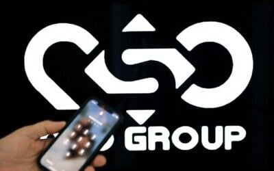 Une illustration photographique montre un téléphone portable près du logo de la société NSO Group dans la ville israélienne de Netanya, le 9 février 2022. (Crédit : JACK GUEZ / AFP)