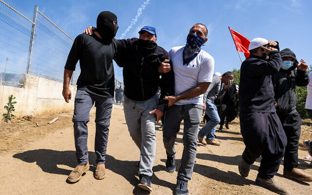 Des membres de la communauté druze portent un manifestant blessé lors des protestations et des émeutes dans leur village de Majdal Shams, sur le plateau du Golan, le 21 juin 2023. (Crédit : Jalaa MAREY / AFP)