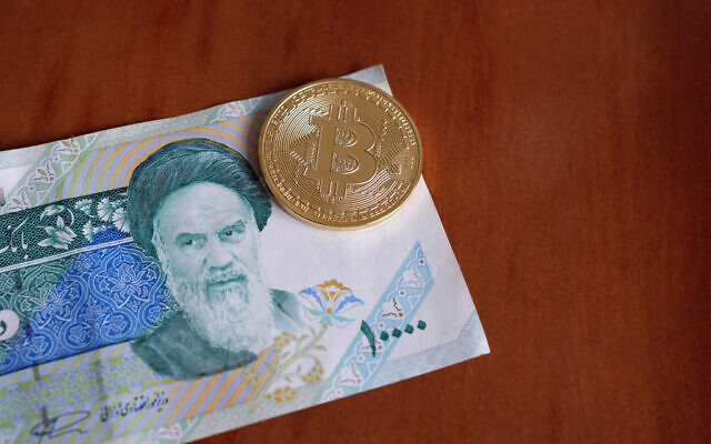 Une pièce de monnaie portant le logo Bitcoin, au-dessus d'un billet de 10 000 rials. Illustration (Crédit : Rainer Puster/iStock Photo by Getty Images) Une pièce de monnaie portant le logo Bitcoin, au-dessus d'un billet de 10 000 rials. Illustration (Crédit : Rainer Puster/iStock Photo by Getty Images)