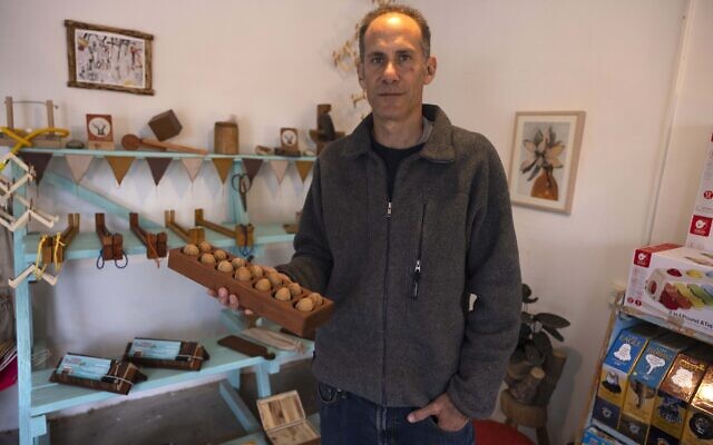 Yuval Vakrat tient un jouet en bois dans sa boutique du kibboutz israélien de Hanita, le 13 avril 2023. - (Crédit : MENAHEM KAHANA / AFP)