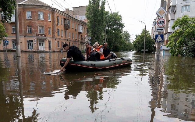 Des bénévoles transportent des habitants sur un bateau pneumatique lors de l'évacuation d'une zone inondée à la suite des dommages subis par le barrage de la centrale hydroélectrique de Kakhovka à Kherson, en Ukraine, le 8 juin 2023. (Crédit : ALEKSEY FILIPPOV/ AFP)
