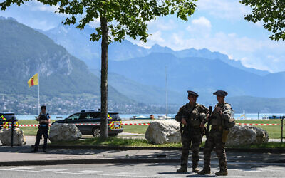 Un officier de police français (à gauche) et un Chasseur Alpin montent la garde près du lac d'Annecy, dans le centre-est de la France, le 8 juin 2023, à la suite d'une attaque au couteau dans la ville alpine française. (Crédit : OLIVIER CHASSIGNOLE / AFP)