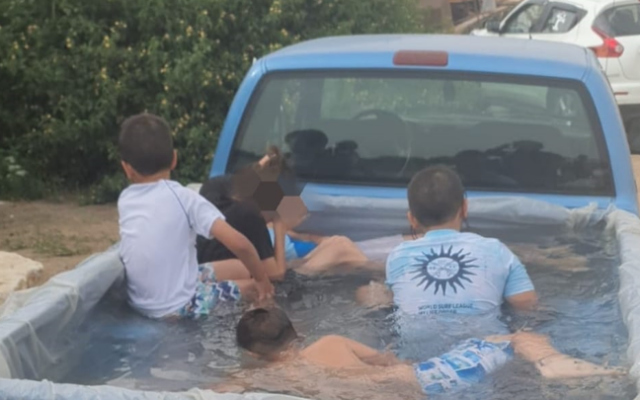 Des enfants jouent dans une piscine improvisée dans le coffre d'une camionnette en juin 2023. (Crédit : Police israélienne)