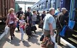 Des personnes montent à bord d'un train d'évacuation dans une gare de Kherson, en Ukraine, le 6 juin 2023, après la destruction d'un important barrage et d'une centrale hydroélectrique dans une partie du sud de l'Ukraine. (Crédit : AP Photo/Nina Lyashonok)