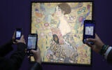 Des personnes prennent des photos de "Dame à l'éventail" de Gustav Klimt lors de son exposition dans les salles de vente de Sotheby's à Londres, le 20 juin 2023. (Crédit : AP/Kirsty Wigglesworth)
