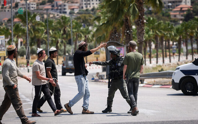 Des soldats israéliens et des partisans du mouvement pro-implantations, le jour où des extrémistes juifs ont incendié des maisons et des véhicules dans la ville, à l'entrée de Turmus Aya, en Cisjordanie, le 21 juin 2023. (Crédit : Yonatan Sindel/FLASH90) Des soldats israéliens et des partisans du mouvement pro-implantations, le jour où des extrémistes juifs ont incendié des maisons et des véhicules dans la ville, à l'entrée de Turmus Aya, en Cisjordanie, le 21 juin 2023. (Crédit : Yonatan Sindel/FLASH90)