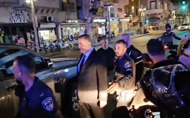 Les manifestants anti-réforme judiciaire réunis contre le ministre de l'Énergie Israel Katz alors que ce dernier retourne sous escorte à sa voiture à Tel Aviv, le 11 juin 2023. (Capture d'écran : Twitter/ used in accordance with Clause 27a of the Copyright Law) Les manifestants anti-réforme judiciaire réunis contre le ministre de l'Énergie Israel Katz alors que ce dernier retourne sous escorte à sa voiture à Tel Aviv, le 11 juin 2023. (Capture d'écran : Twitter/ used in accordance with Clause 27a of the Copyright Law)