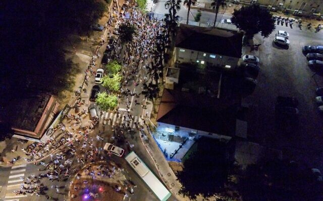 Des manifestants se rassemblent devant le poste de police de Petah Tikva le 26 juin 2023, où un militant anti-réforme judiciaire est interrogé. (Crédit : Frères et Sœurs d'Armes)