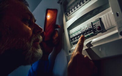 Un homme vérifiant une boîte à fusibles lors d'une panne de courant. (Crédit : Jovanmandic/iStock at Getty Images)